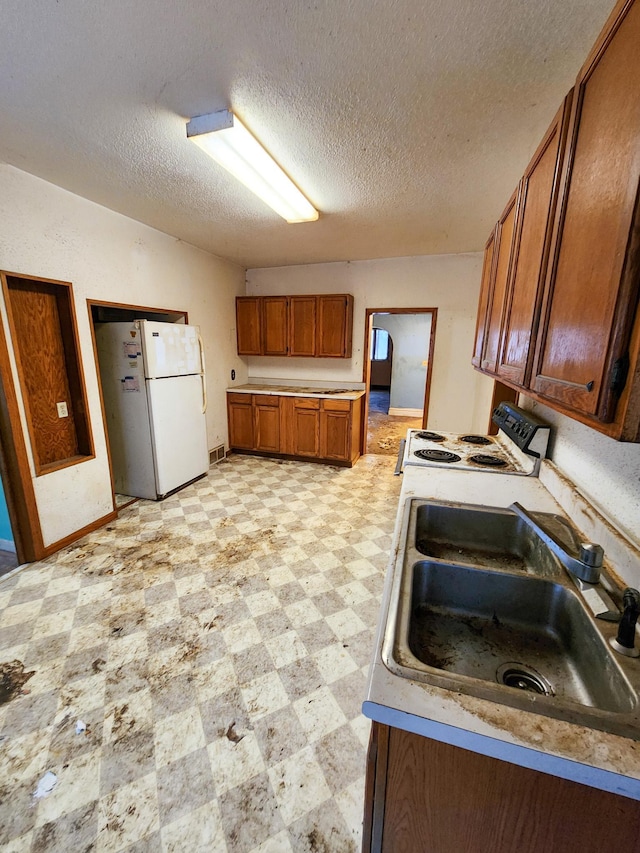 kitchen with a textured ceiling, sink, and white appliances