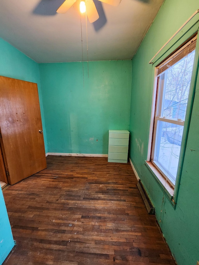 unfurnished room with dark hardwood / wood-style flooring, ceiling fan, and a baseboard heating unit