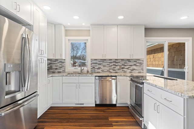 kitchen with stainless steel appliances, dark wood-style flooring, white cabinets, and light stone counters