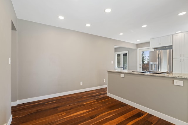 kitchen with light stone countertops, dark wood-style floors, white cabinetry, and stainless steel refrigerator with ice dispenser