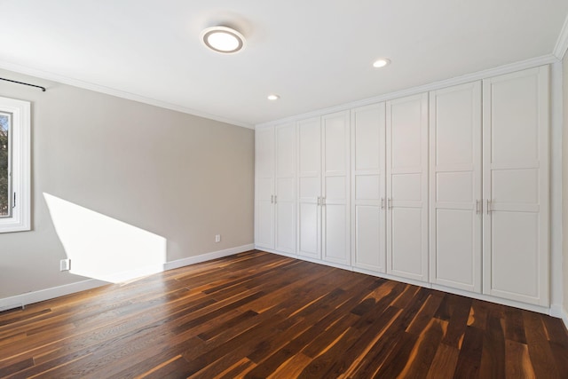 unfurnished bedroom with recessed lighting, dark wood-style flooring, baseboards, ornamental molding, and a closet