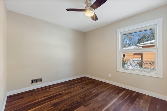 spare room with dark wood-style floors, visible vents, ceiling fan, and baseboards