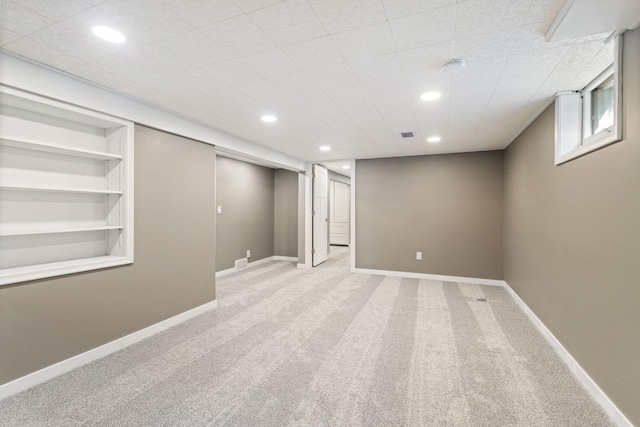 basement featuring built in features, recessed lighting, light carpet, and baseboards