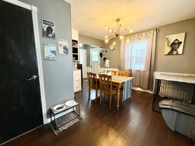 dining area with dark hardwood / wood-style floors, a wealth of natural light, and an inviting chandelier