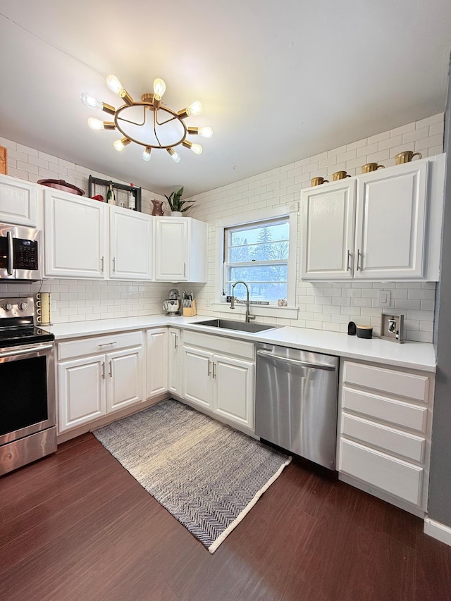 kitchen with white cabinets, appliances with stainless steel finishes, dark wood-type flooring, and sink