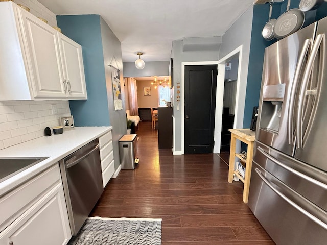 kitchen with hanging light fixtures, dark hardwood / wood-style floors, decorative backsplash, white cabinetry, and stainless steel appliances