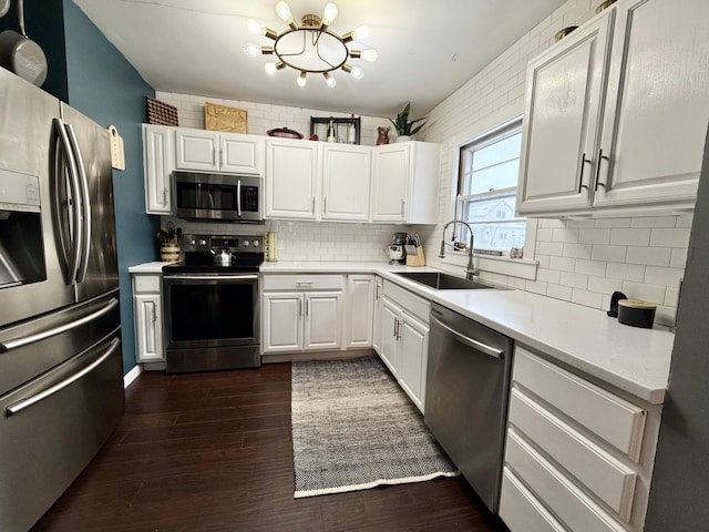 kitchen with white cabinets, a sink, dark wood-style flooring, light countertops, and stainless steel appliances