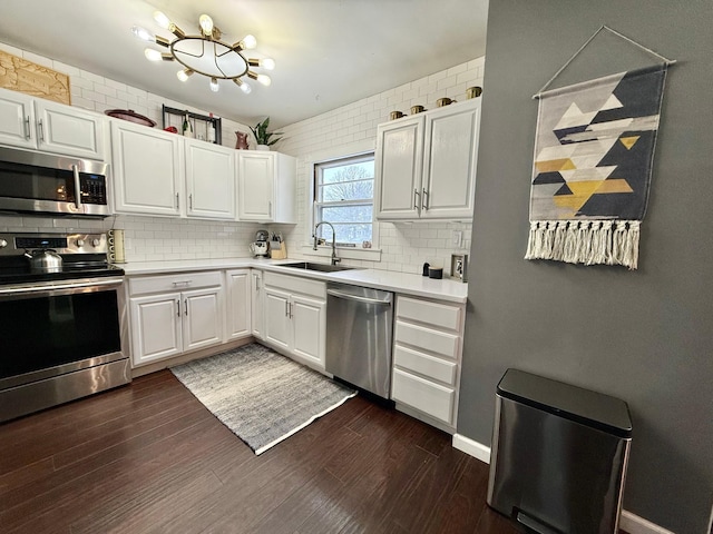 kitchen with a sink, dark wood-style flooring, light countertops, stainless steel appliances, and decorative backsplash