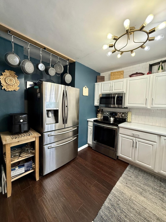 kitchen featuring light countertops, white cabinetry, stainless steel appliances, dark wood-type flooring, and decorative backsplash