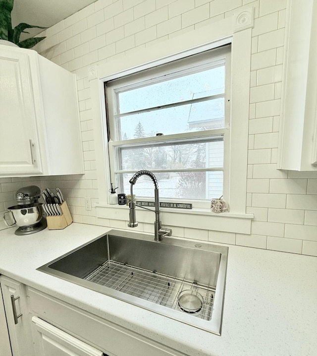 kitchen featuring white cabinets, plenty of natural light, a sink, light countertops, and decorative backsplash