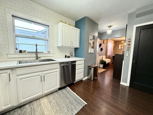 kitchen featuring light countertops, backsplash, dark wood-type flooring, stainless steel dishwasher, and a sink