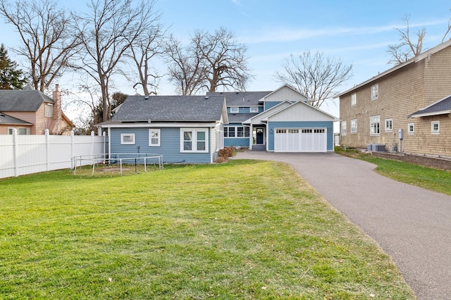 view of front of house featuring cooling unit, fence, driveway, a front lawn, and a trampoline