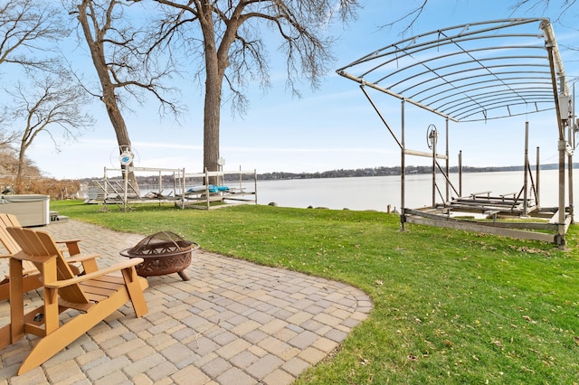 exterior space featuring a dock, a fire pit, a water view, boat lift, and a patio area