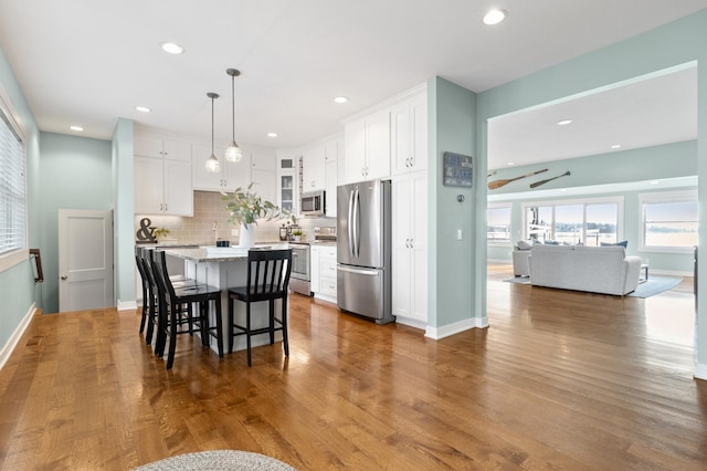 kitchen featuring a kitchen breakfast bar, white cabinets, appliances with stainless steel finishes, and a center island