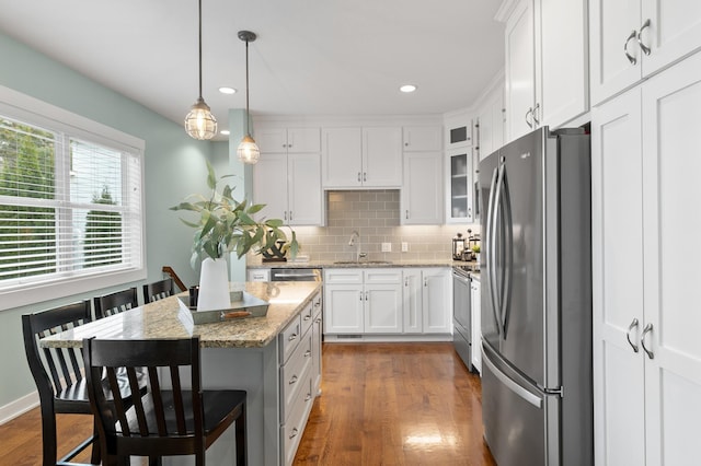 kitchen featuring a sink, backsplash, freestanding refrigerator, stove, and dark wood-style flooring