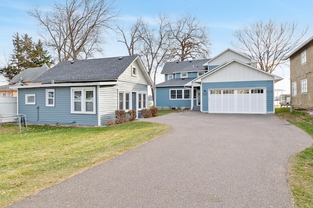 view of front of home with roof with shingles, an attached garage, a front lawn, aphalt driveway, and a trampoline