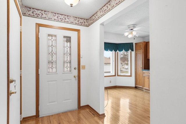 entryway featuring ceiling fan, light hardwood / wood-style flooring, and a textured ceiling