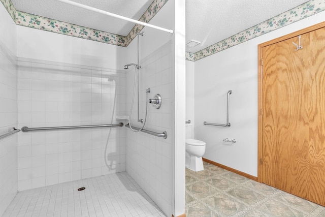 bathroom with tile patterned floors, toilet, a textured ceiling, and tiled shower