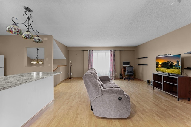 living room with a textured ceiling, light hardwood / wood-style floors, and a notable chandelier