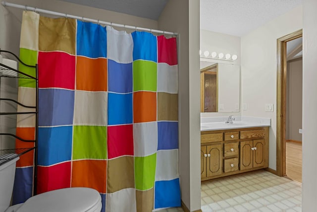 bathroom with vanity, curtained shower, toilet, and a textured ceiling