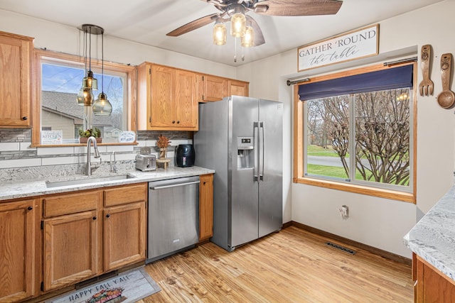 kitchen with sink, stainless steel appliances, light hardwood / wood-style flooring, backsplash, and pendant lighting