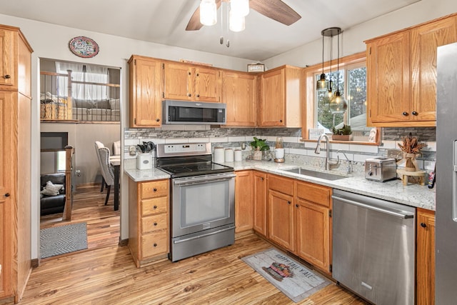 kitchen with sink, stainless steel appliances, tasteful backsplash, light hardwood / wood-style flooring, and pendant lighting