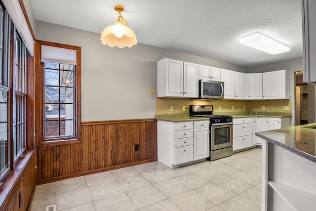 kitchen featuring decorative light fixtures, stainless steel appliances, a textured ceiling, and white cabinets