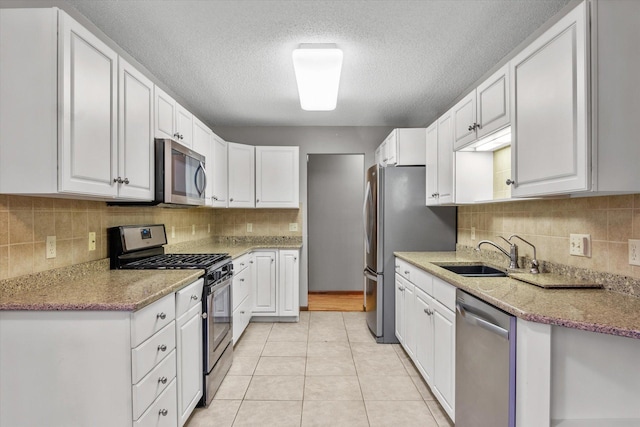 kitchen featuring stainless steel appliances, white cabinets, sink, and light tile patterned floors