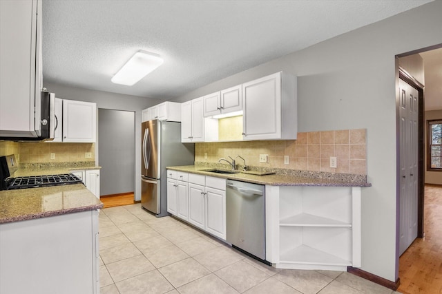 kitchen with sink, white cabinetry, a textured ceiling, light stone countertops, and appliances with stainless steel finishes