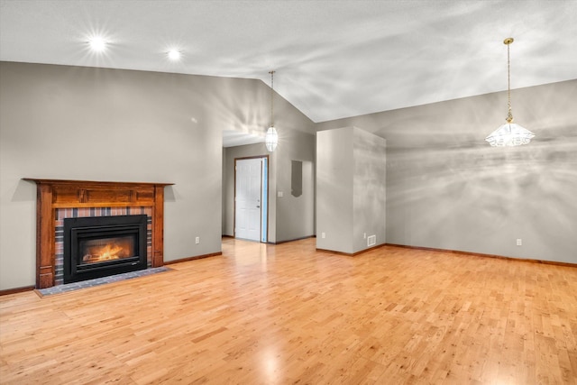 unfurnished living room with light hardwood / wood-style floors, an inviting chandelier, and vaulted ceiling