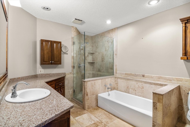 full bathroom featuring a textured ceiling, toilet, vanity, and shower with separate bathtub