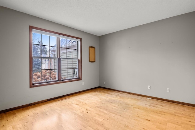 empty room with a textured ceiling and light wood-type flooring