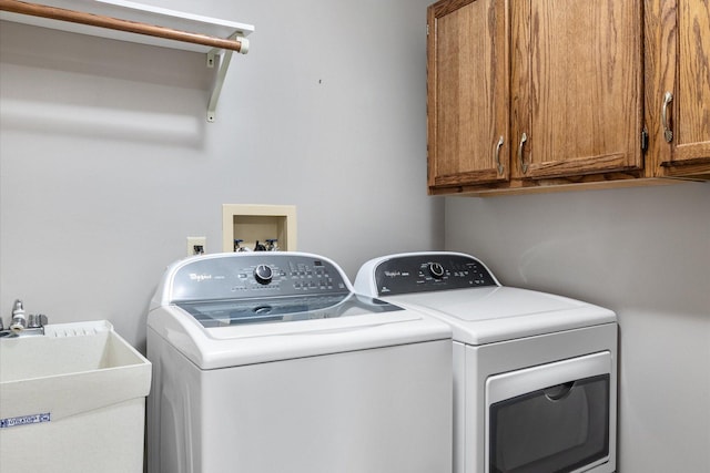 clothes washing area featuring sink, washing machine and clothes dryer, and cabinets