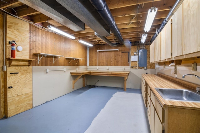 basement featuring sink, a workshop area, wooden walls, and electric panel