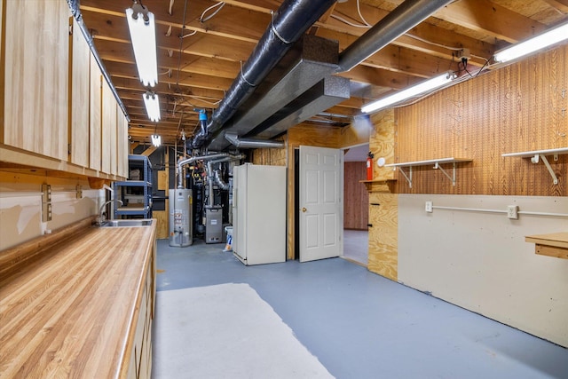 basement with sink, white refrigerator, and water heater