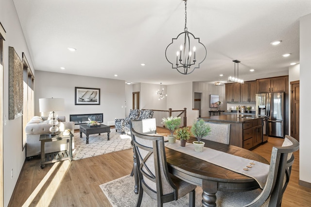 dining space featuring sink, light hardwood / wood-style flooring, and a chandelier