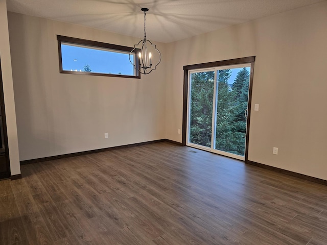 unfurnished room with dark hardwood / wood-style floors, a notable chandelier, and a textured ceiling