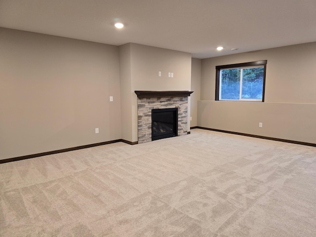 unfurnished living room with light colored carpet and a stone fireplace