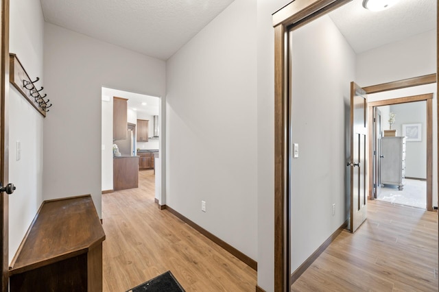 corridor featuring a textured ceiling and light wood-type flooring