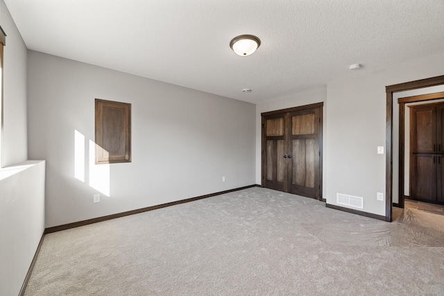 unfurnished bedroom with light colored carpet and a textured ceiling