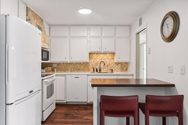 kitchen featuring sink, dark hardwood / wood-style flooring, backsplash, white appliances, and white cabinets