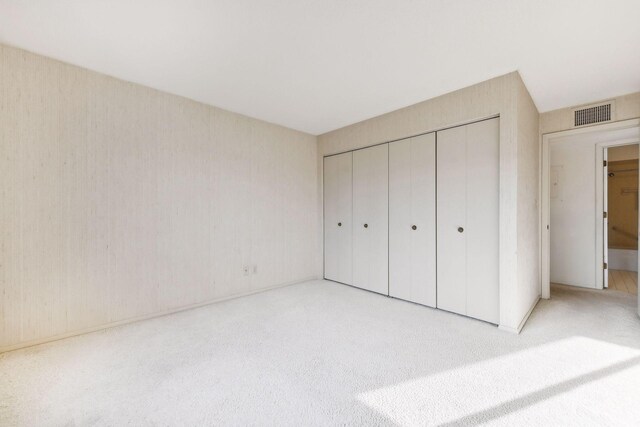 unfurnished bedroom featuring a closet and light carpet