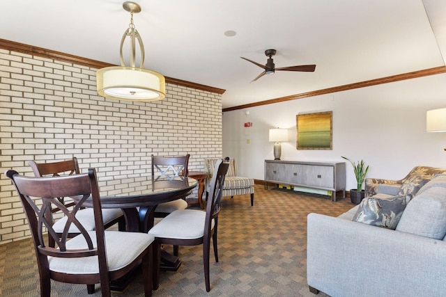 carpeted dining room with ornamental molding, brick wall, and ceiling fan