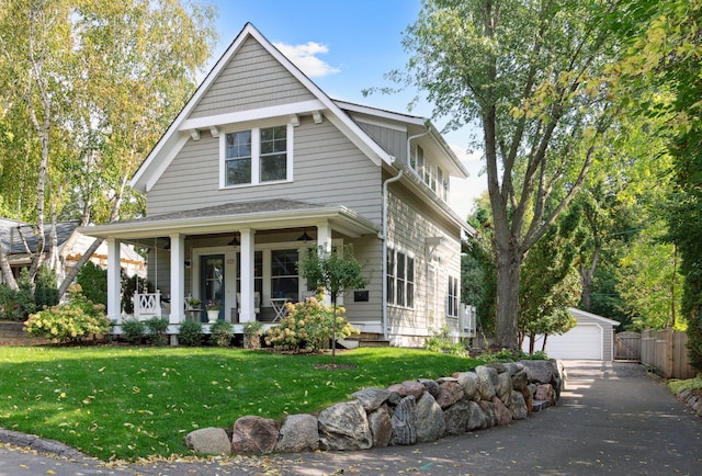 view of front of property with covered porch, a garage, an outdoor structure, and a front lawn