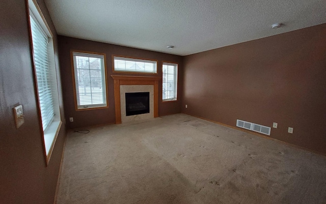 unfurnished living room featuring a textured ceiling, light carpet, and a fireplace