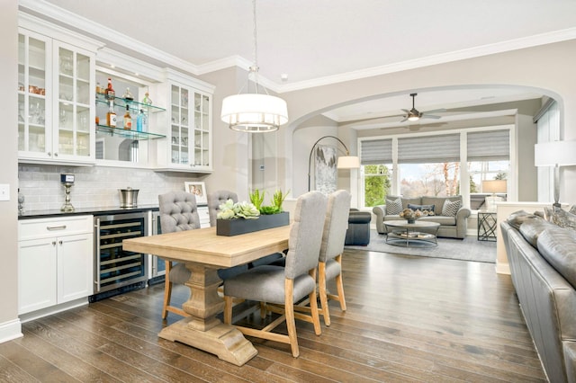 dining area featuring wine cooler, ceiling fan, dark wood-type flooring, and crown molding