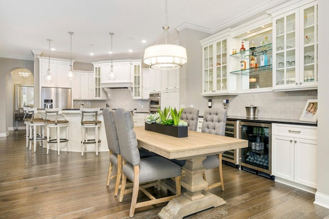 dining space featuring dark hardwood / wood-style flooring, crown molding, and wine cooler