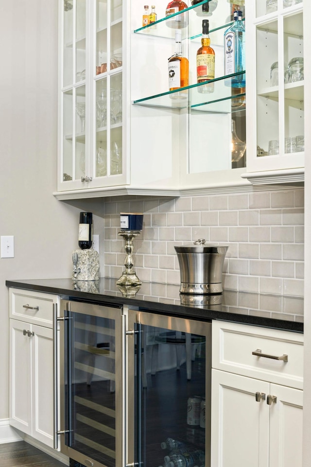 bar with tasteful backsplash, white cabinetry, and beverage cooler