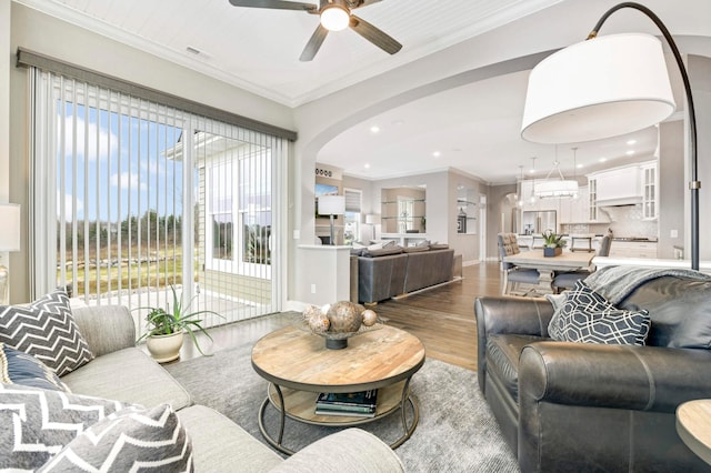 living room with ceiling fan, wood-type flooring, and crown molding