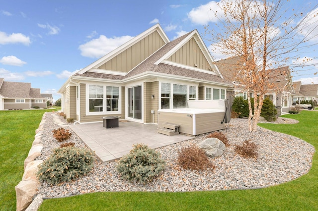 rear view of house featuring a patio area, a yard, and a hot tub